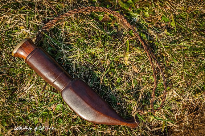 Small Puukko knife with leather sheath on grass in sunlight. Colour Landscape. © P. Maton 2015 whittleandstitch.net